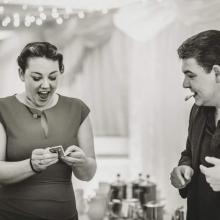 Wedding Magician Darren Brand  wows a lady with a surprised playing card appearing in her hand.